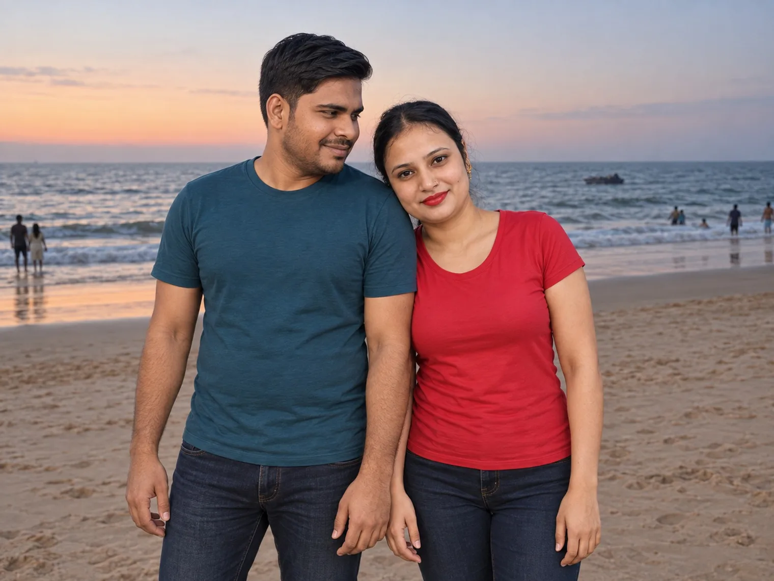 Nav and Vandana standing close together on Calangute beach, the sea and a few people at the water's edge behind them under a pink and orange sky.